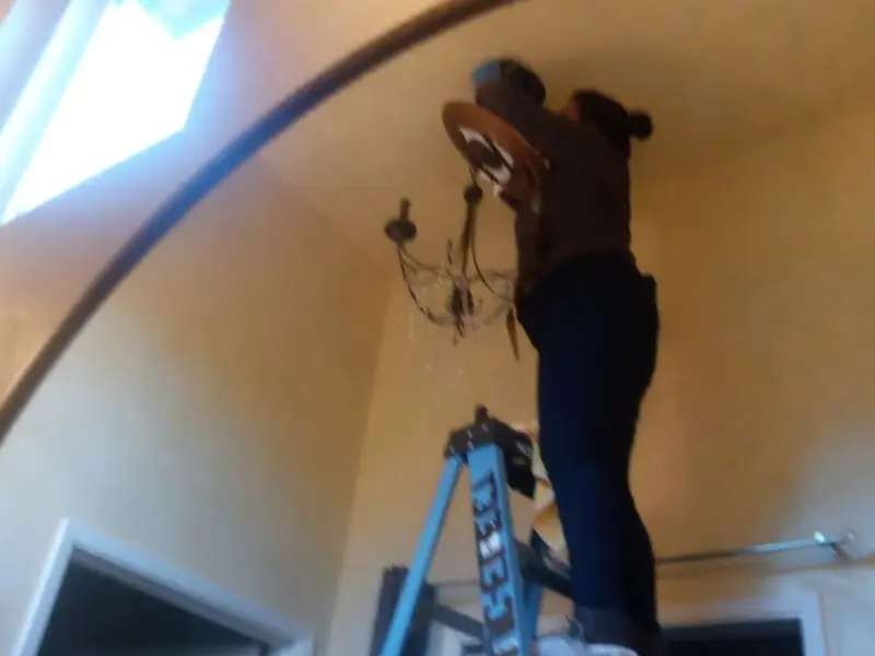 Electrician installing a chandelier in a Barre residence